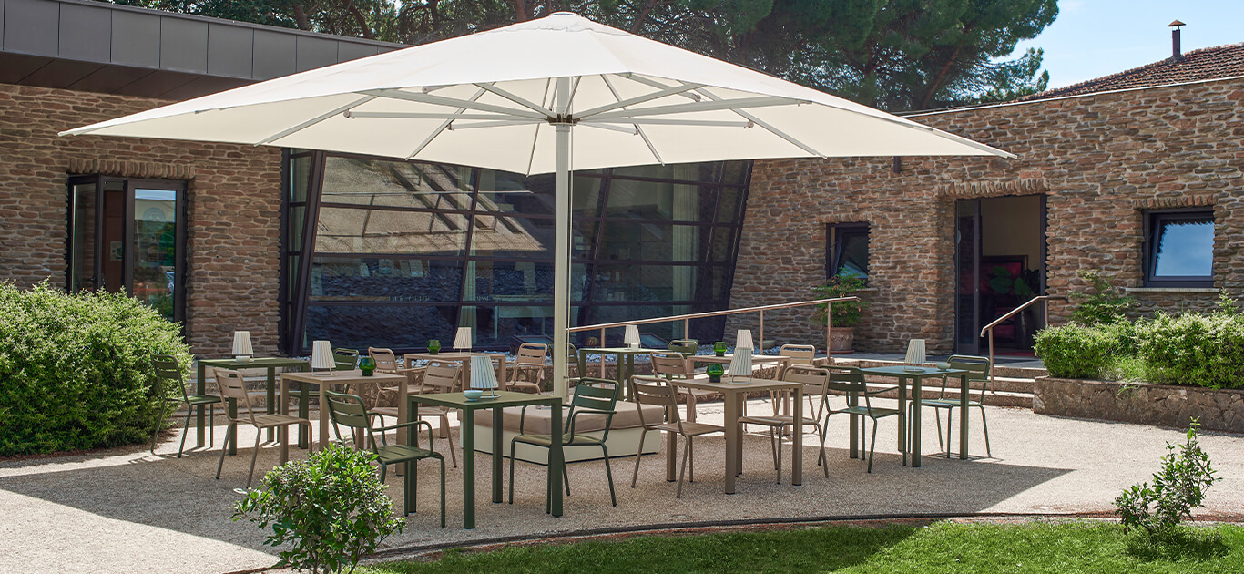 Maggiore, design Christophe Pillet, un maxi ombrellone disponibile nelle dimensioni 5x5, 6x6 e diametro 7 che consente una copertura di spazi da 25 a 50 metri quadrati. La sua ampiezza è ideale per l’utilizzo contract poichè consente la mise en place di numerosi tavoli e sedute. Inoltre, la possibilità di aggiungere il cuscino sul basamento permette di usare lo stesso come una seduta dining. L’estrema praticità del meccanismo di apertura e chiusura, il sistema antivento, gli snodi in alluminio dal design tecnologico rendono l’ombrellone funzionale ed elegante. La collezione si completa di accessori quali il kit luci led dimmerabili, gronda di scolo e sistemi di fissaggio a terra.